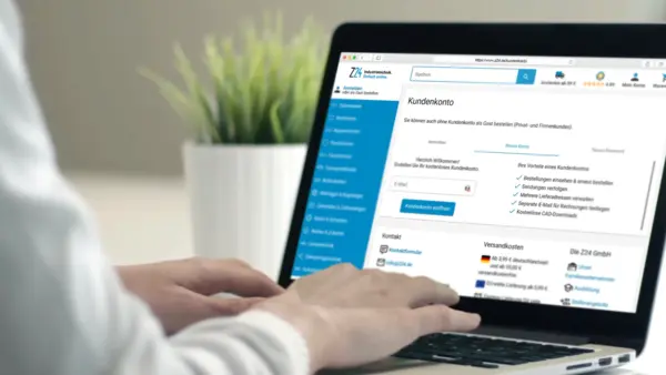 Zwei Hände tippen auf einem Laptop, auf dem das Kundenkonto-Anmeldefenster der Z24-Website geöffnet ist.