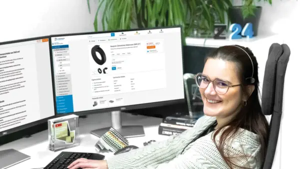 Mitarbeiterin im Kundenservice sitzt am Schreibtisch vor zwei Monitoren und berät online im Z24-Shop.